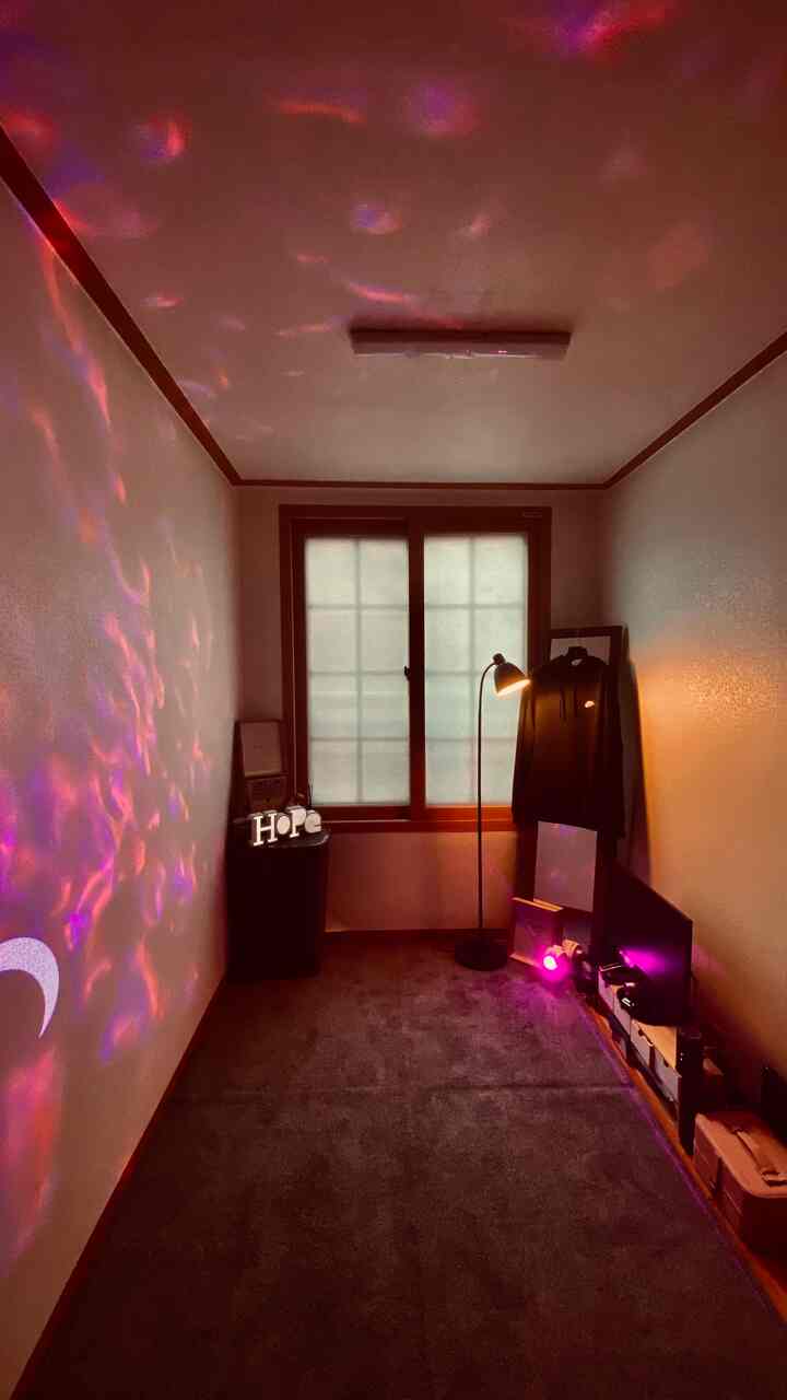 Warm beige and brown toned small studio apartment featuring a rug, floor lamp, picture frames, and mood lighting creating a cozy atmosphere