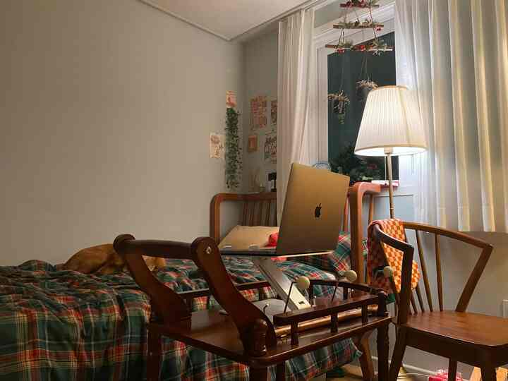 Natural wood tones and plaid blanket highlight a bedroom featuring a vintage trolley cart and a MacBook Pro for a cozy home office setup