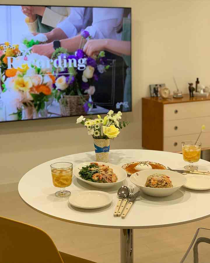 Bright white and beige toned dining room featuring a round dining table with plates and a vase in a cozy atmosphere