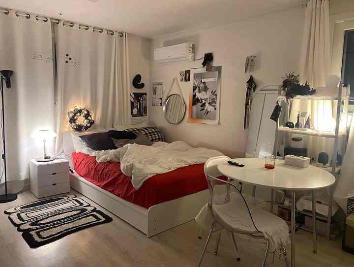 Compact studio bedroom in white and red tones, featuring simple cozy furnishings and decor