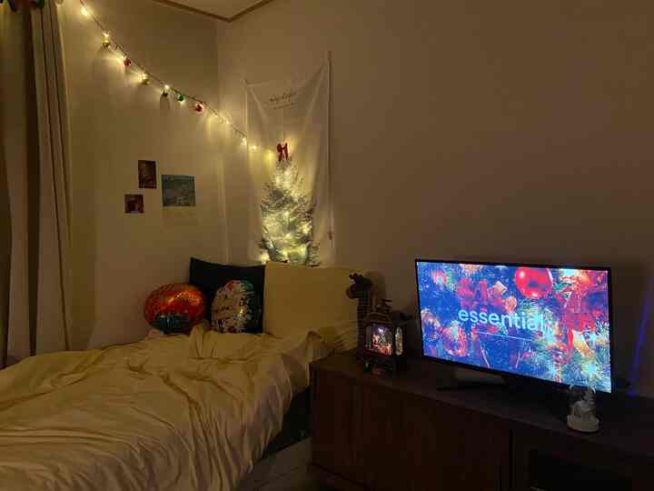 黄色のトーンが特徴の小さな寝室、クリスマスのガーランドとライトで温かみのある雰囲気のあるインテリア
