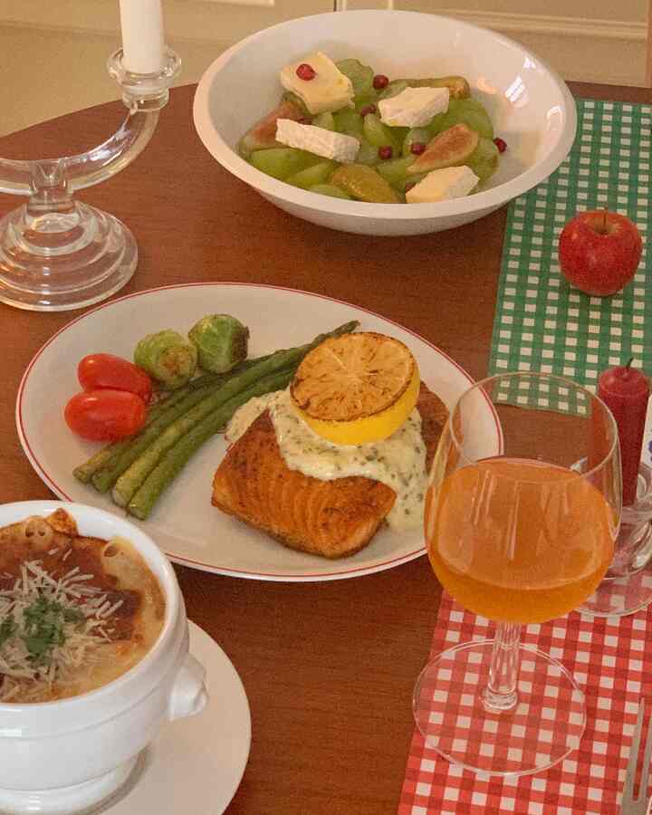 温かみのある木目調のキッチンテーブルに複数の食器とオレンジ色の飲み物が置かれた、ヴィンテージ風のホームパーティーの雰囲気あるインテリア