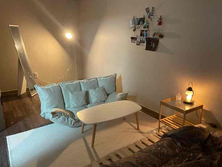 白と木目調のワンルームリビング、座椅子ソファと木製テーブル、温かい照明が居心地の良い雰囲気を演出するインテリア