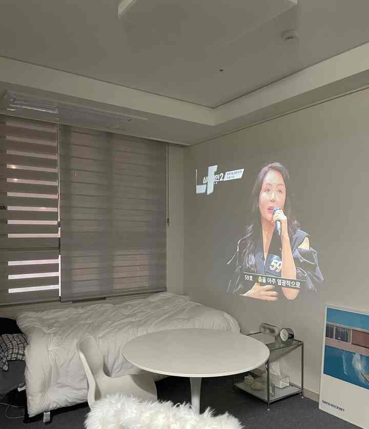 Natural and white toned studio apartment featuring a bed and round table in a modern interior