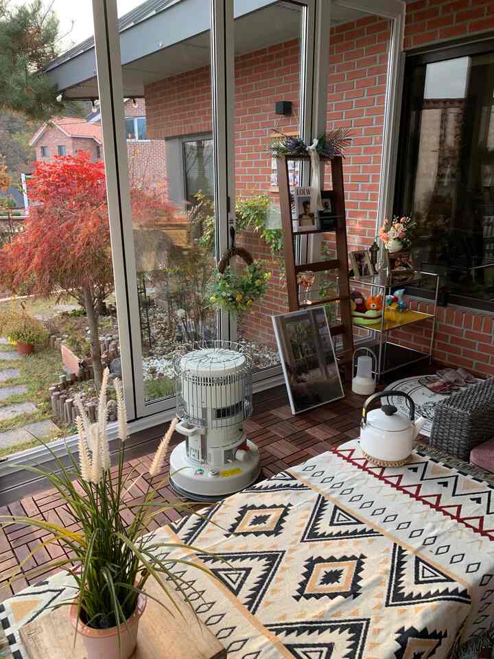 Cozy country house terrace featuring warm wood tones, patterned rug, a camping heater, and charming decorative elements