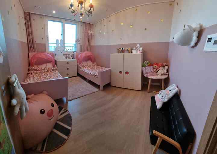 ピンク色の壁と二つの子供用ベッドが配置されたシンプルで清潔感のある子供部屋のインテリア