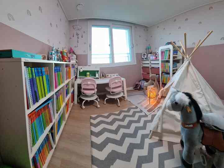 Pastel pink and natural tone kids' room featuring desks, bookshelves, and an Indian tent in a neat, cozy space