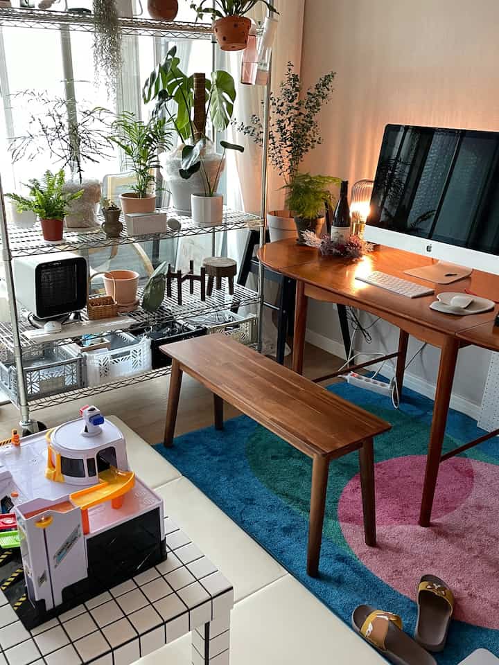 Wood-toned home office featuring a wooden desk and bench, colorful rug, and multiple plants creating a cozy interior