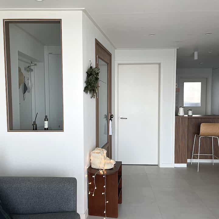 A clean and serene entrance with white and gray tones, harmonizing with a wood-accented kitchen space