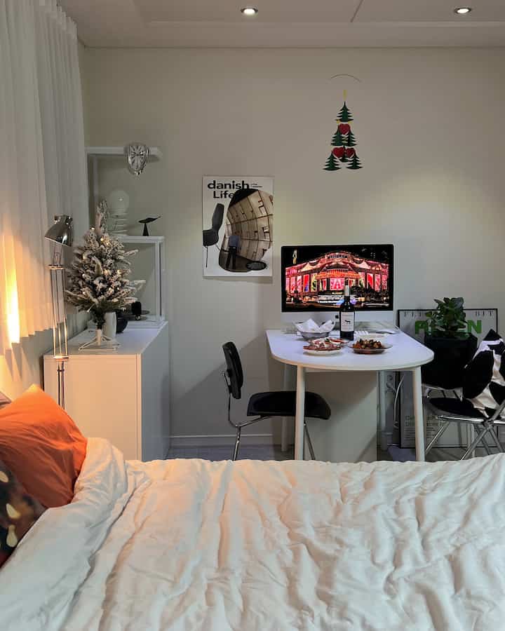 White and black toned studio bedroom featuring a dining table set with home party food and wine in a cozy atmosphere