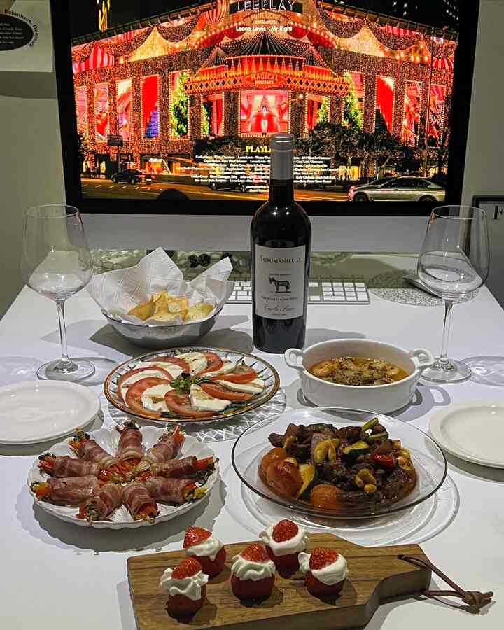White table featuring wine, plates with assorted dishes, creating a home cafe and home party atmosphere