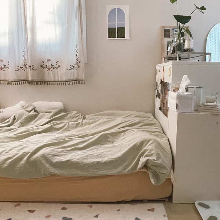 Beige and white toned studio bedroom featuring a bed and cabinet, creating a warm and cozy atmosphere