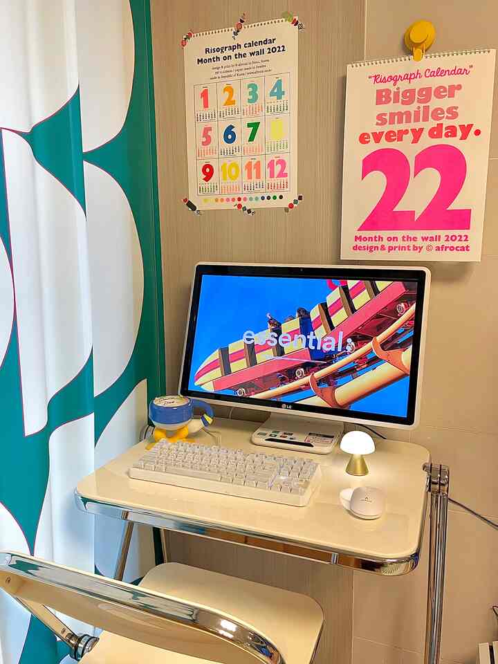 A white and green toned compact home office corner in living room featuring a folding table and gaming keyboard in a tidy setup
