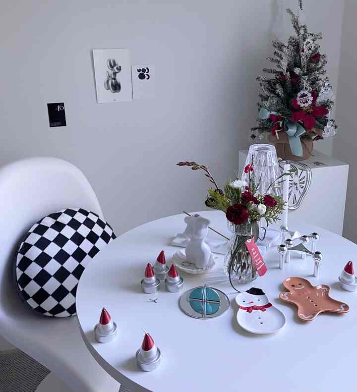 White-toned studio apartment featuring a round table with Christmas decor and a vase, creating a modern atmosphere