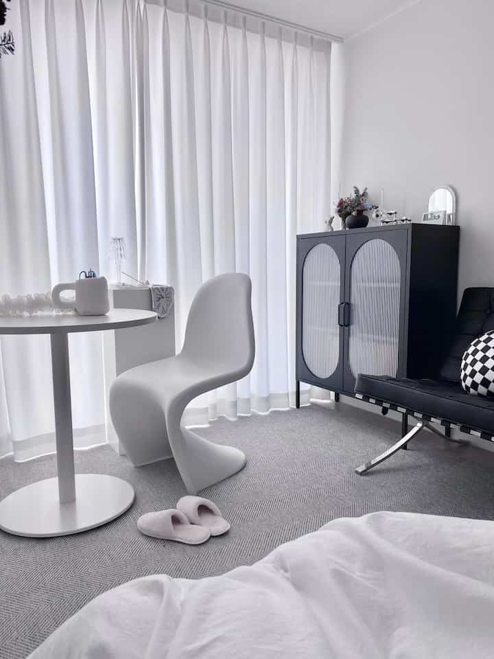 White and black studio apartment living space featuring a round dining table and modern design sofa in a simple modern interior