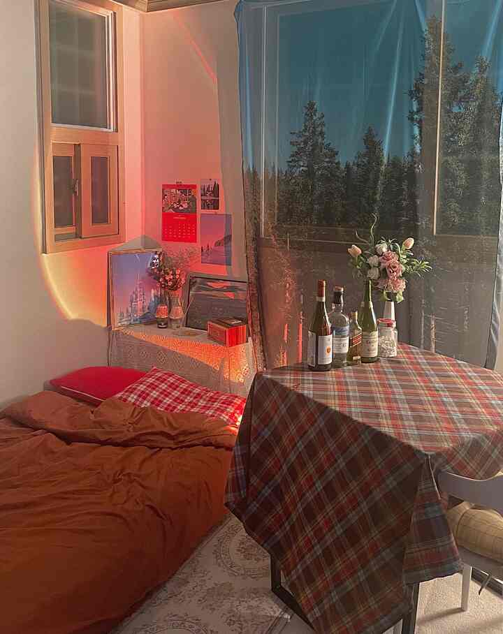 白い壁とブラウンのベッドカバーが調和する4.5畳の小さな寝室、ホームパーティー用の小さなダイニングテーブルとムードある照明を備えた印象的な空間