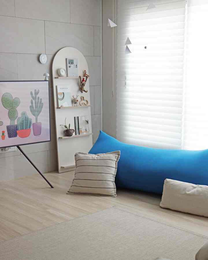 Bright wooden floor living room featuring a blue bean bag and white blinds with a simple, natural atmosphere