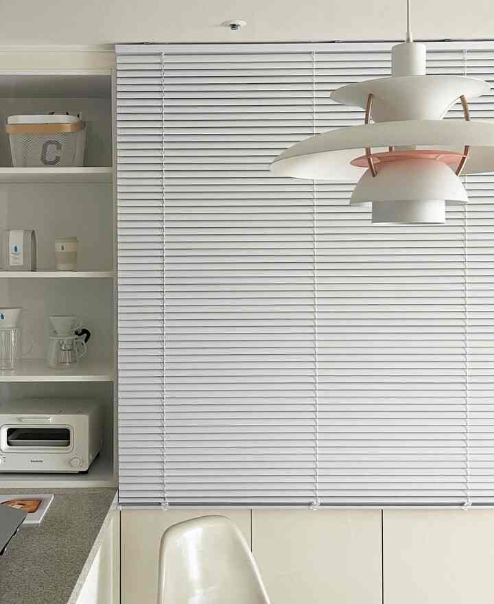 White-toned kitchen featuring neat blinds and a modern pendant light with a clean atmosphere