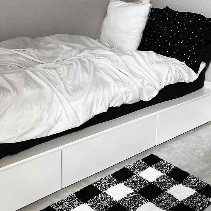 Monotone black and white bedroom featuring a bed with clean storage drawers under, creating a simple modern space