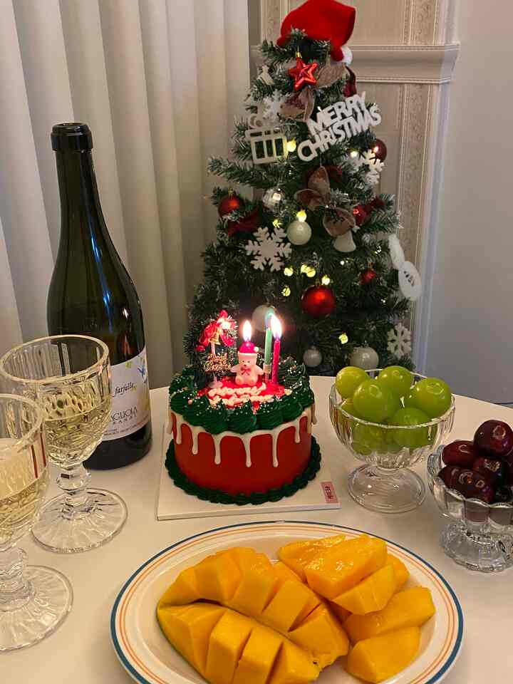 赤と緑のクリスマスカラーのリビング、ケーキとワイングラスが置かれたホームパーティーテーブル