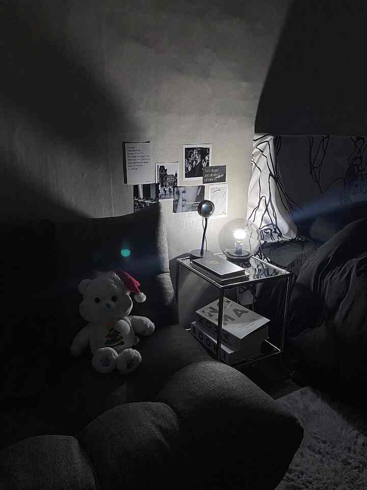 Gray toned bedroom featuring dark gray sofa, side table with mood lighting creating cozy atmosphere