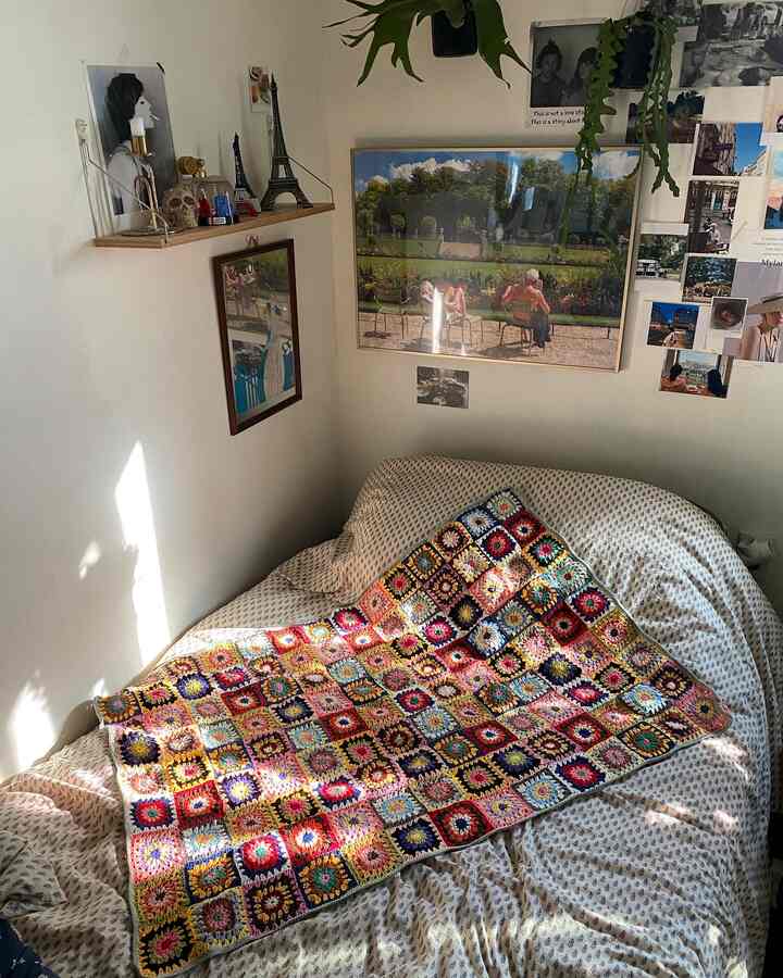 ナチュラルな色調の居心地の良い一人暮らしの部屋、多彩なビンテージ風クロシェブランケットとポスターが配置されたボヘミアンスタイルのインテリア