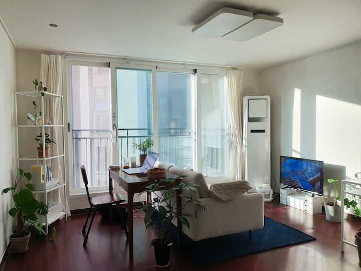 Bright ivory and brown toned living room featuring a sofa and desk dividing the space with a cozy atmosphere