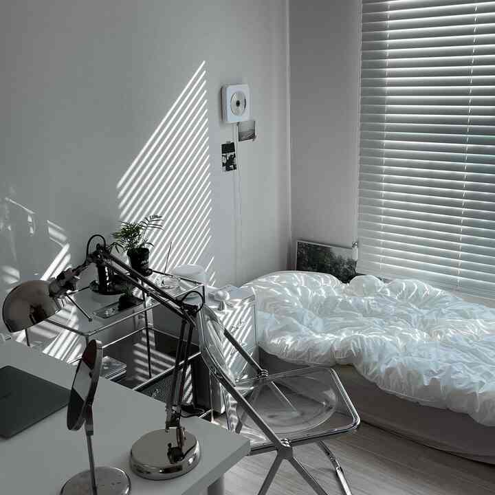 ホワイトトーンの寝室、透明な椅子と机が配置された清潔感あるモダンな空間