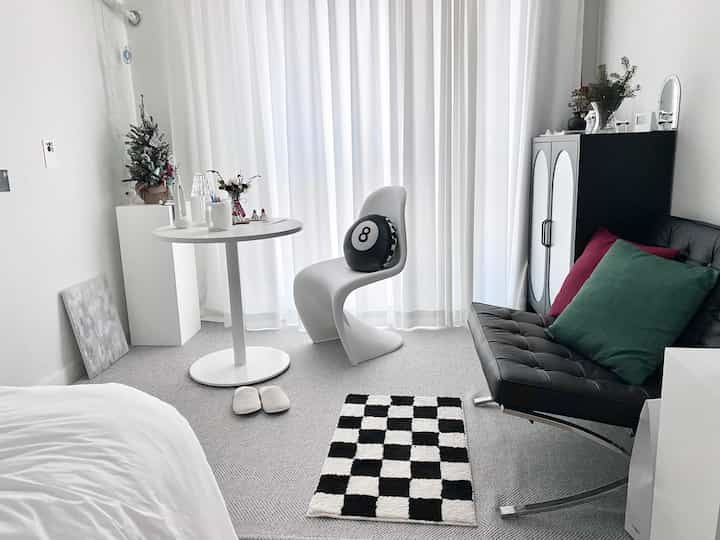 White and black toned studio apartment featuring a modern sofa and checkerboard rug with a simple atmosphere
