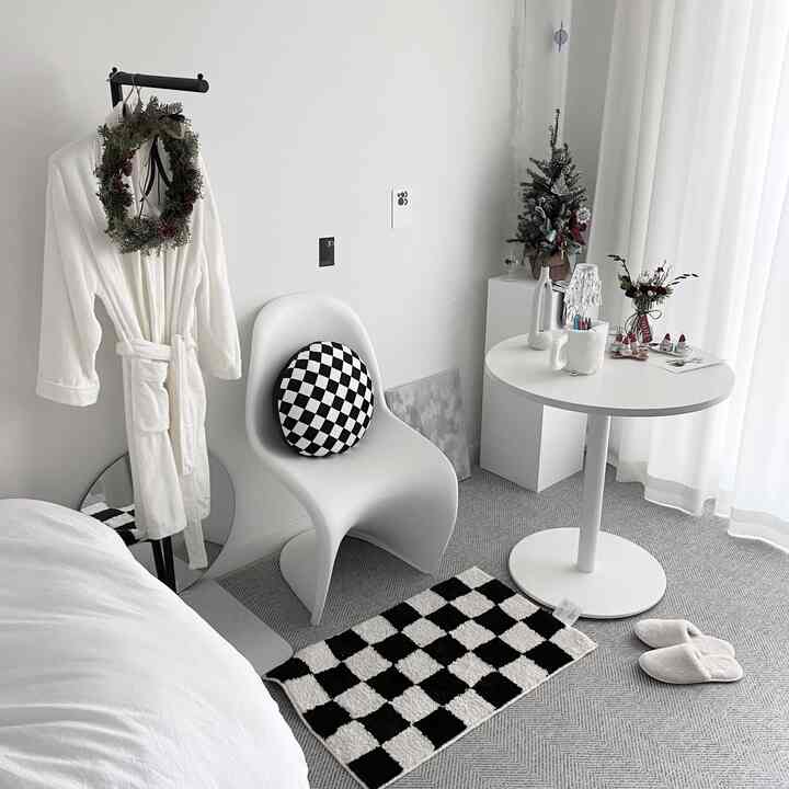 Modern living room in white and black tones featuring checkerboard cushion and rug with a clean and cozy atmosphere