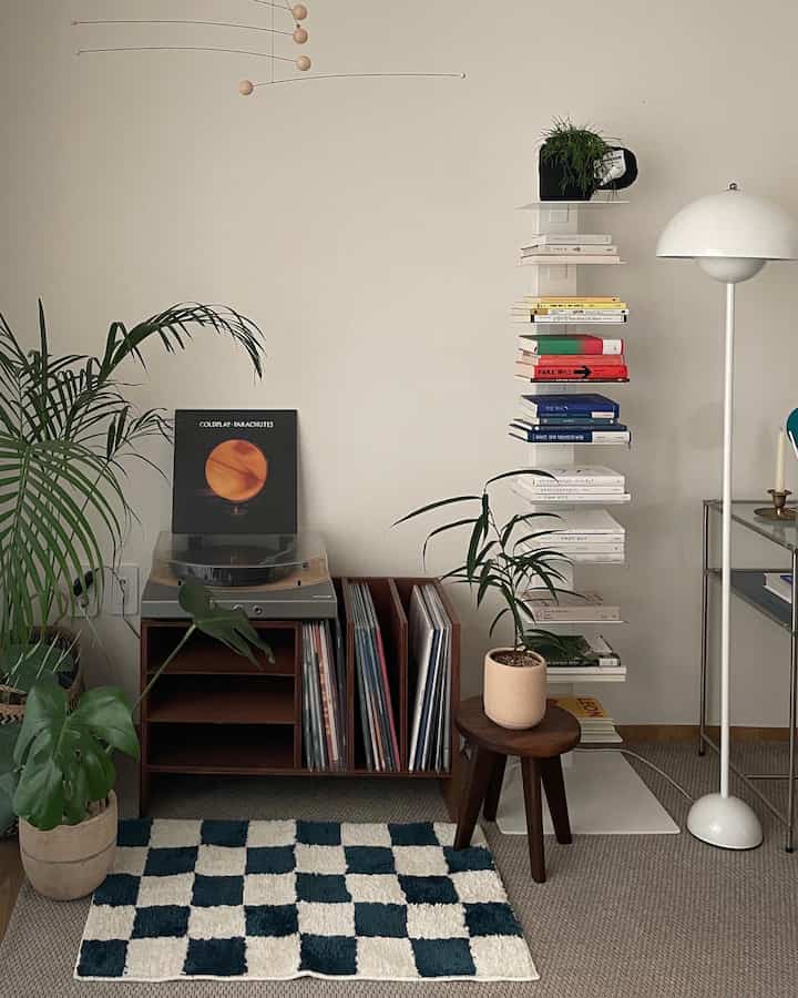 White-walled home styling space featuring brown furniture, record storage cabinet, and a floor lamp creating a cozy atmosphere