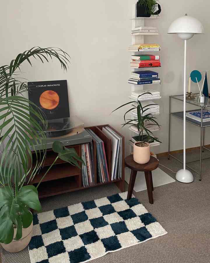 Nordic style living room with natural wood tones, white walls, and green plants; retro LP storage and floor lamp create a cozy atmosphere