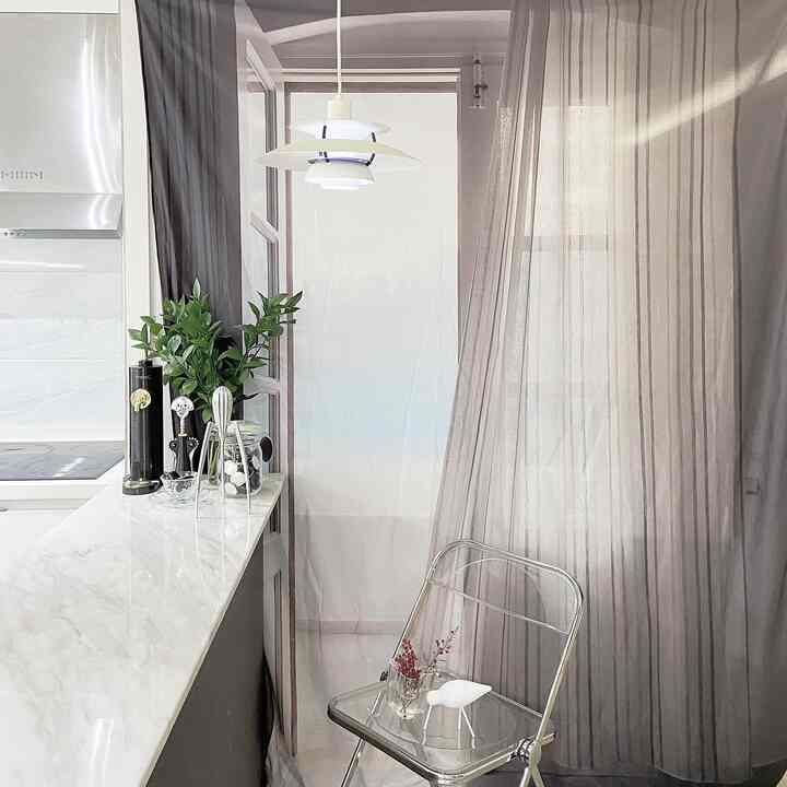 ホワイトとグリーン調のキッチン空間、透明なシルバーチェアとペンダントライトが配置された清潔で自然な雰囲気のインテリア