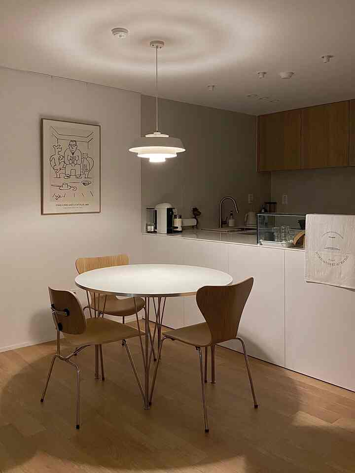 白とウッドトーンが調和するキッチン兼ダイニング、円形テーブルとペンダントライトが配置された自然な雰囲気のインテリア