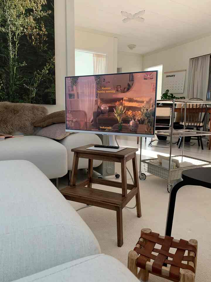 白とウッドトーンのリビング、モニターとスツール、キッチンカートが配置された明るくすっきりとした雰囲気のインテリア