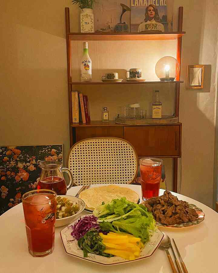Cozy home cafe space in a small room featuring warm wood tones, white dining table, vintage plates, and mood lighting