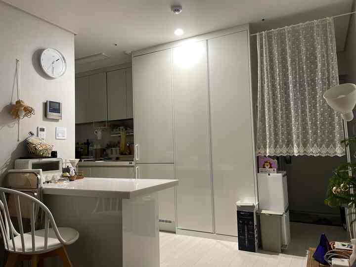 White-toned kitchen and entrance area featuring a kitchen island and chairs with a clean, modern interior