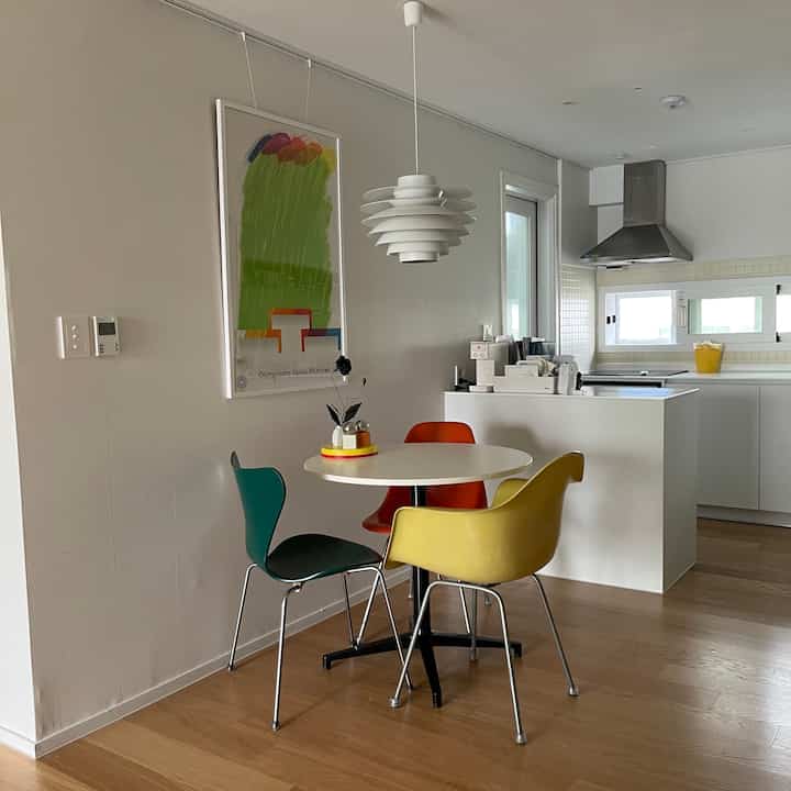 Compact kitchen in white and wood tones featuring a round dining table with colorful chairs creating a cozy atmosphere