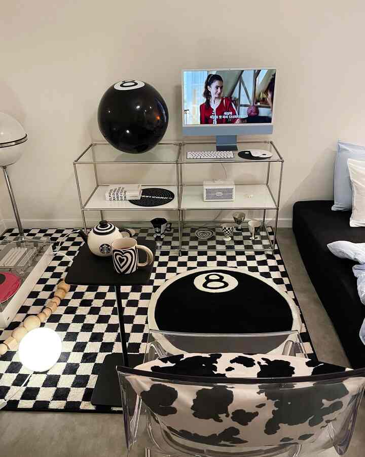 Monotone bedroom featuring modular shelves with iMac and checkerboard rug, showcasing a clean modern interior