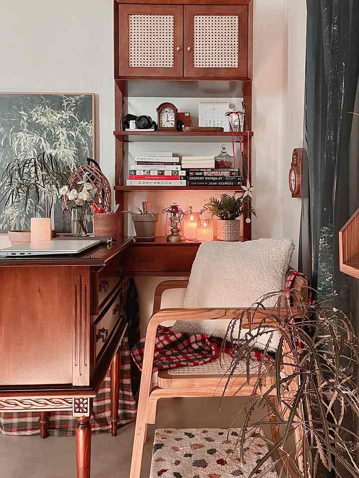 Warm wood tones with vintage furniture, candles, and plants arranged in a cozy home office space