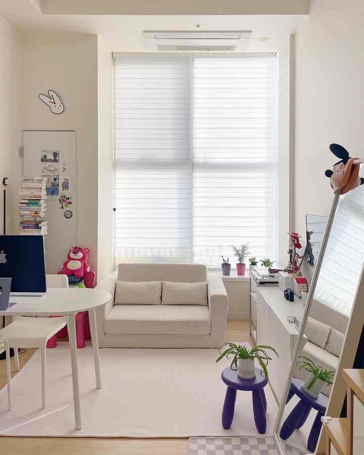 Small home office space in white and natural tones featuring a central sofa, desk with monitor, and large full-length mirror on the right with clean interior design