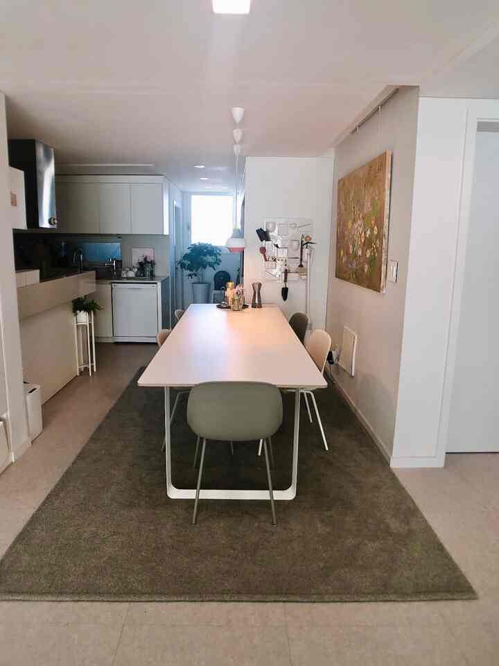 Modern and minimal kitchen dining area in white and brown tones, featuring a sleek dining table with chairs and wall art for warmth