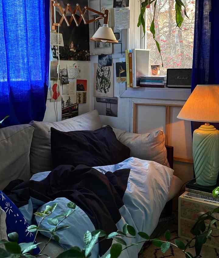 Blue and beige toned bedroom featuring a cozy sofa and posters with a warm atmosphere
