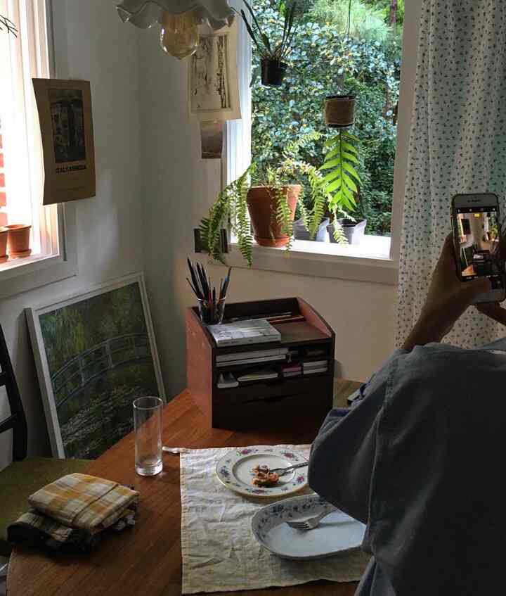 白い壁と木目調のダイニングテーブル、豊富な植物が配置された自然で温かみのあるキッチンまたはダイニングルームの雰囲気のあるインテリア