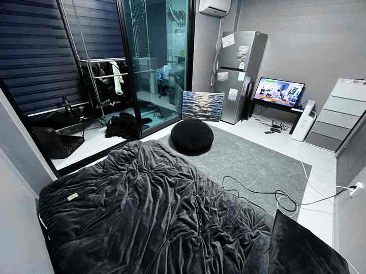 Gray-toned studio bedroom featuring black bedding and a TV stand with a modern atmosphere