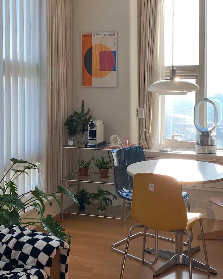 A white and brown toned dining room featuring a dining table by the window and a cozy home cafe area under natural light