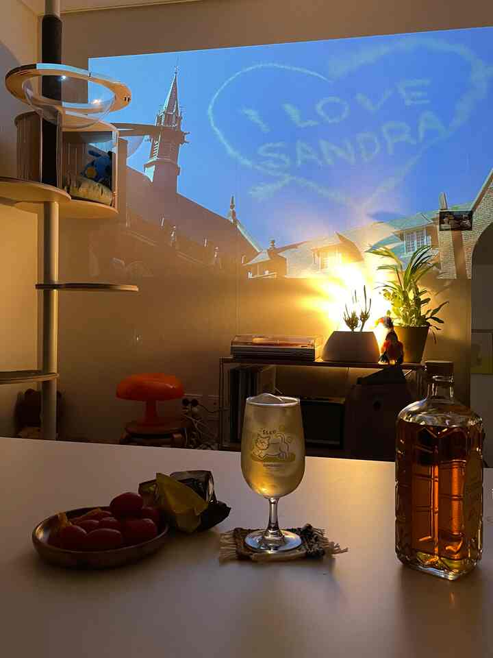 Warmly lit living room featuring a cat tower and large projector screen creating a cozy atmosphere