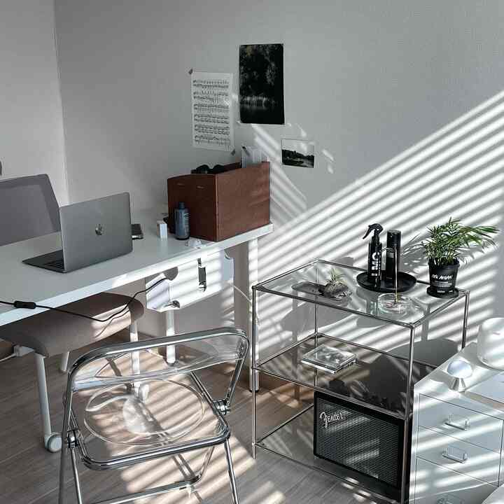 White and wood tone home office for remote work, featuring a transparent acrylic chair and glass shelving in a clean, minimal design