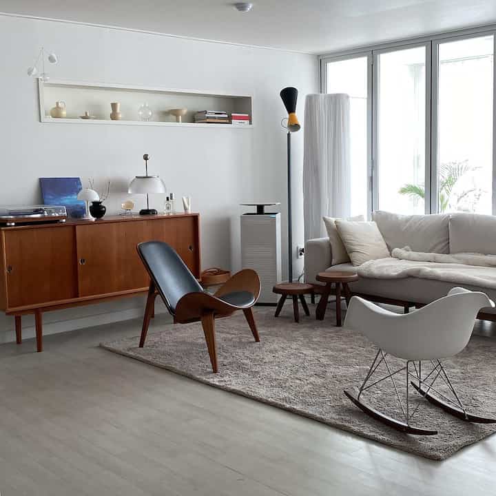 Natural and wood tone living room featuring minimalist furniture arrangement and large windows creating a bright, clean space