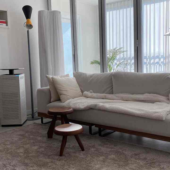 Bright natural-toned living room featuring a beige sofa and brown wooden stools in a calm atmosphere